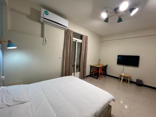 a bedroom with a white bed and a flat screen tv at 市區背包客棧 有套房可包棟 in Jincheng