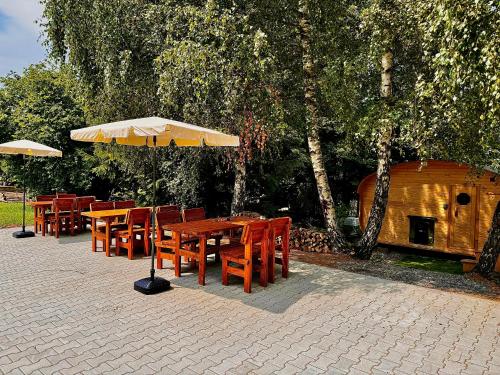 a row of wooden tables and chairs with an umbrella at Paseky Apartments Resort in Nové Město na Moravě
