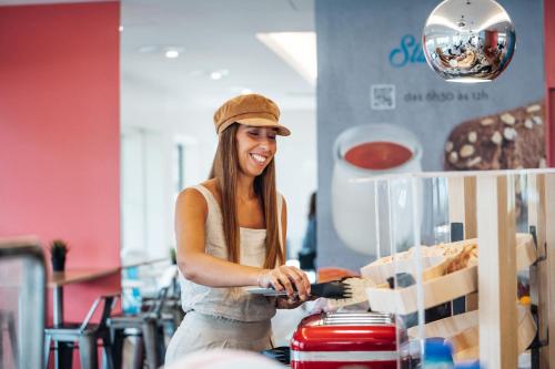 a woman is smiling while standing behind a counter at Stay Hotel Porto Centro Trindade in Porto