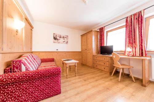 a living room with a red couch and a desk at Garni Hotel Residence Diamant in San Vigilio Di Marebbe