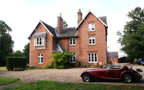 an old red car parked in front of a house at Sam's Stable in Bungay