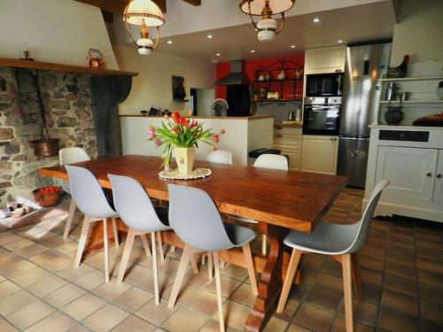 a kitchen with a wooden table and white chairs at Gîte La Part des Anges in Saint-Angel