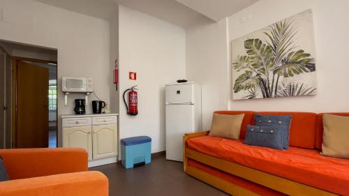 a living room with a orange couch and a kitchen at Verde Pino in Vilamoura
