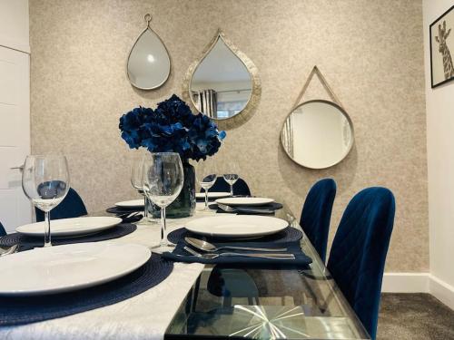 a dining table with blue chairs and mirrors at Home Away Luxury Living - Horley in Horley
