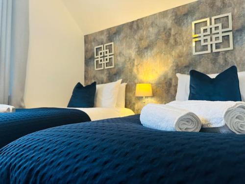 a bedroom with two beds with blue and white pillows at Home Away Luxury Living - Horley in Horley