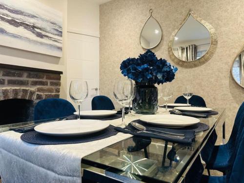 a dining table with plates and a vase of blue flowers at Home Away Luxury Living - Horley in Horley