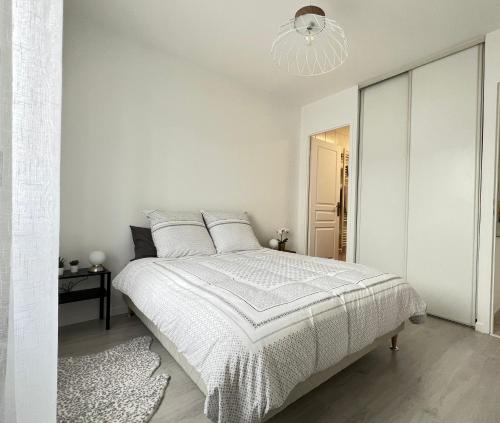 - une chambre blanche avec un lit et un lustre dans l'établissement Appartement Coquelicot 25km Paris et Disney, à Pontault-Combault
