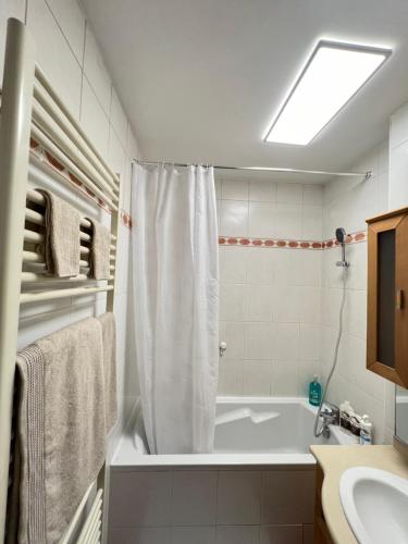 une salle de bain blanche avec une baignoire et un lavabo dans l'établissement Appartement Coquelicot 25km Paris et Disney, à Pontault-Combault