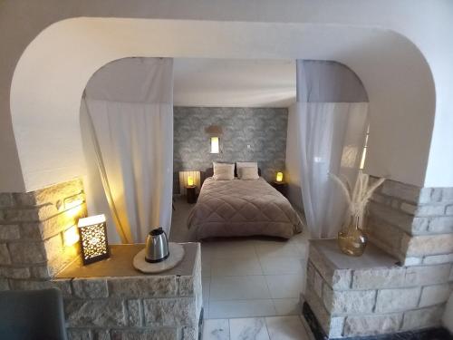 une chambre avec un lit et un mur en pierre dans l'établissement Le Nid du Cormier, à Ville-Saint-Jacques