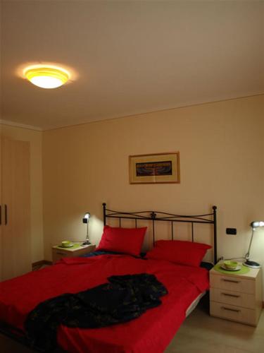 a bedroom with a red bed with two red pillows at Arcobaleno Dante in Arizzano