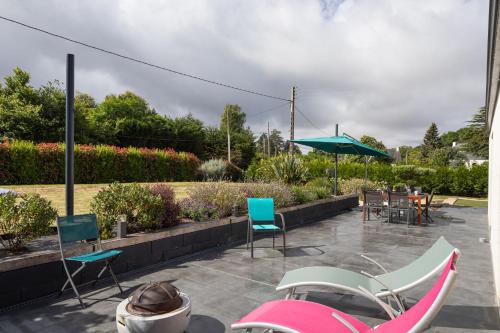 a patio with chairs and tables and an umbrella at L'échappée du Cap - Proche de la mer in Plévenon