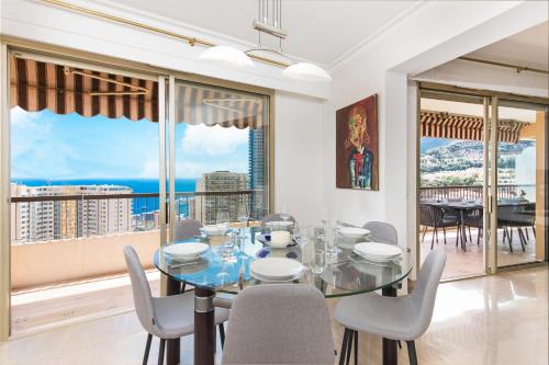 une salle à manger avec une table et des chaises et une grande fenêtre dans l'établissement MONTEVERDI - Appartement 150 m2 - Frontière Monaco - Parking, à Beausoleil