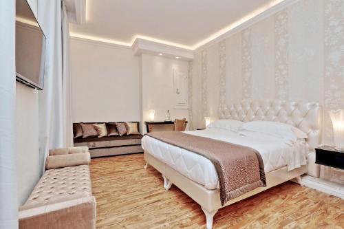 a white bedroom with a large bed and a couch at BQ House COLOSSEUM Luxury Rooms in Rome