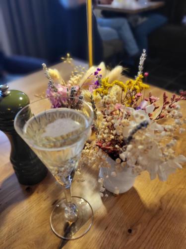 a vase of flowers and a wine glass on a table at Hotel Restaurant Alte Stadtmauer in Beilstein
