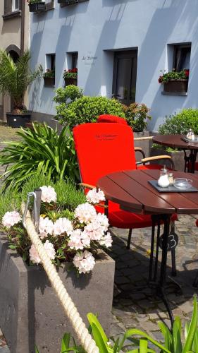 two red chairs and a table and some flowers at Hotel Restaurant Alte Stadtmauer in Beilstein