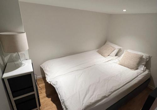 a bedroom with a bed with white sheets and pillows at Studio apartment in Sogndal