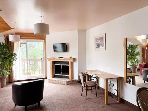 a living room with a table and chairs and a fireplace at Auberge du Jardin in Petit-Saguenay