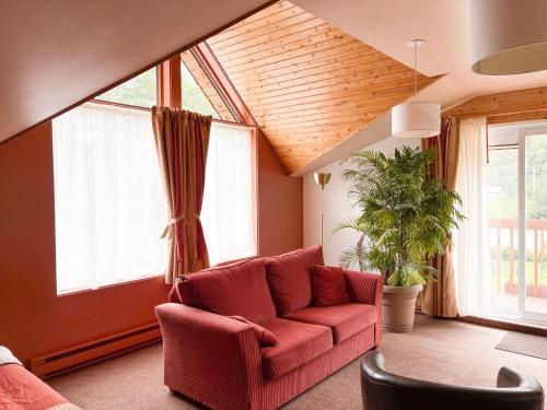 a living room with a red couch and windows at Auberge du Jardin in Petit-Saguenay