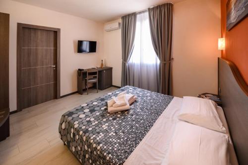 a hotel room with a bed and a television at Hotel Rainbow Resort in Marsala