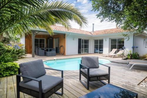 un patio avec deux chaises et une piscine dans l'établissement Villa proche du bassin -piscine, à Gujan-Mestras
