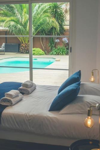 une chambre avec un lit avec des oreillers et une piscine dans l'établissement Villa proche du bassin -piscine, à Gujan-Mestras