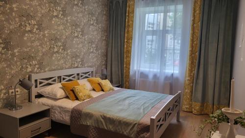 Un dormitorio con una cama con almohadas amarillas y una ventana. en Apartment on Brivzemnieka, en Liepāja
