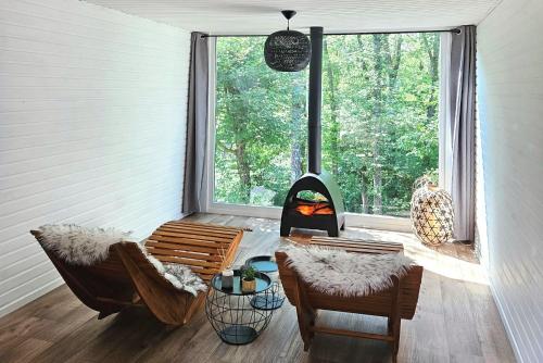 Una sala de estar con chimenea y sillas frente a una ventana. en CHALET ARDENTARDENNE - Durbuy, en Durbuy