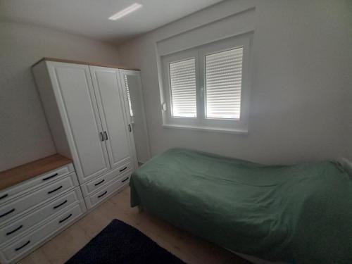 a bedroom with a bed and a dresser and a window at Apartman Dina in Peroj