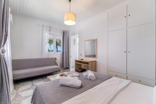 a white bedroom with a bed and a couch at Elia Perigiali Lefkada in Nydri