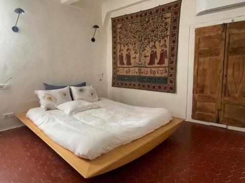 un lit dans une chambre avec un tableau sur le mur dans l'établissement La Farigoulette - Vieux village, à Saint-Saturnin-lès-Apt