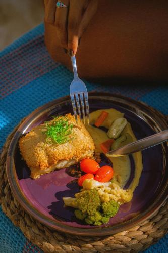 a person holding a fork over a plate of food at Café Jeri Hotel - Adults Only in Jericoacoara