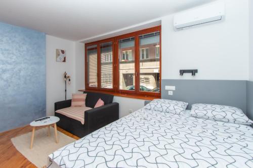 萨拉热窝Apartman Bene的一间卧室，里面有一张床、一把椅子和一扇窗户。