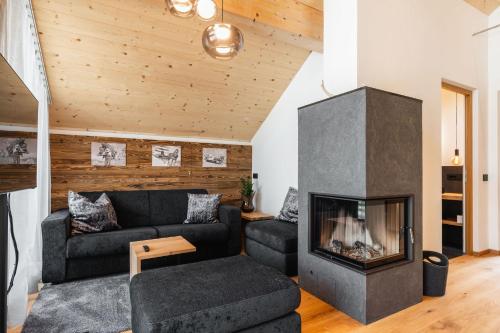a living room with a black couch and a fireplace at Chalet Lumis in San Vigilio Di Marebbe