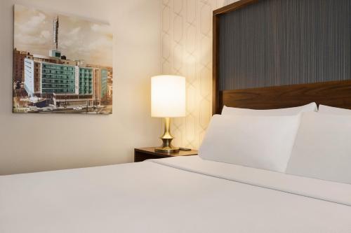 a bedroom with a large white bed and a lamp at The American Hotel Atlanta Downtown, Tapestry Collection by Hilton in Atlanta