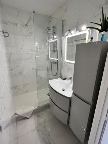 une salle de bain blanche avec un lavabo et une douche dans l'établissement CAP D'AGDE Naturiste Heliopolis - PLUME, au Cap d'Agde