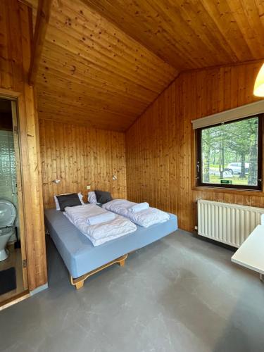 una camera da letto con un letto in una stanza di legno di Arhus Cottage and Camping a Hella