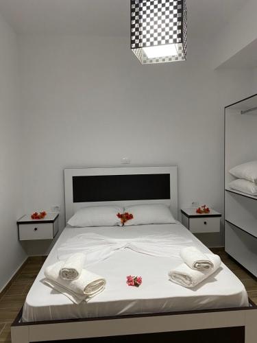 a bedroom with a white bed with towels on it at Rentrooms Geni in Ksamil