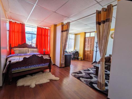 a bedroom with a bed with red curtains and a rug at Monoestudio Sicuani in Sicuani