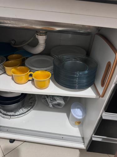 a shelf with plates and bowls in a cabinet at Casa da Pri in Rio das Ostras