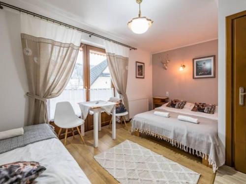 a bedroom with two beds and a table and a window at Domek z Góralską Duszą Śleboda in Jurgów