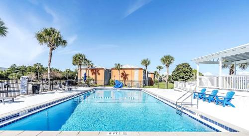 a swimming pool with blue chairs and palm trees at Copper Cay Family Friendly Central Location in Destin