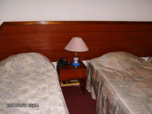 a hotel room with two beds and a lamp on a table at Olhos Pretos in Caldas da Rainha