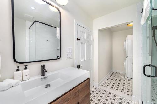 a white bathroom with a sink and a mirror at The Marigold - Gorgeously remodelled PEC farmhouse in West Lake