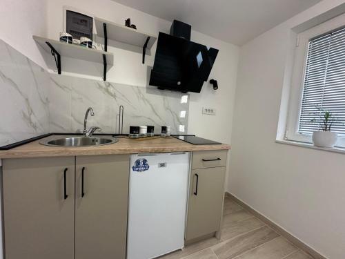 a kitchen with a sink and a tv on the wall at Julia Apartments in Ohrid