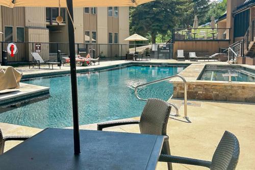 a table with an umbrella next to a swimming pool at Snowmas Village 20C in Snowmass Village