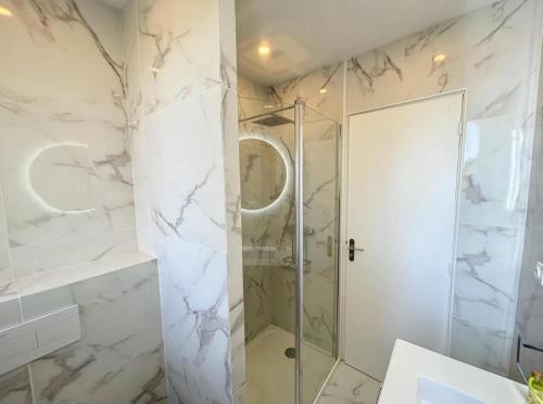 La salle de bains est pourvue d'une douche et de murs en marbre blanc. dans l'établissement Spacieux appartement à Nice 4 chambres, à Nice