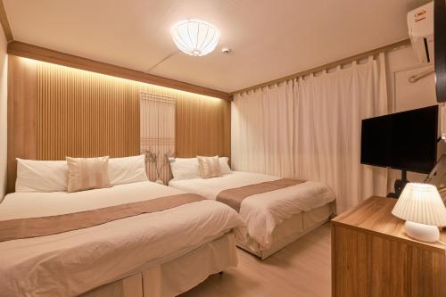 a hotel room with two beds and a flat screen tv at Zen House,Jamsil Seoul in Seoul