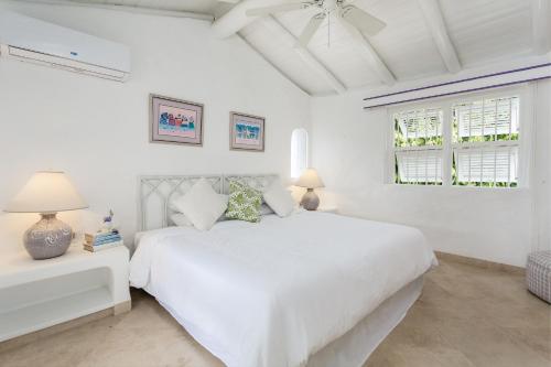 a white bedroom with a white bed and two windows at Merlin Bay Beach Villas in Saint James
