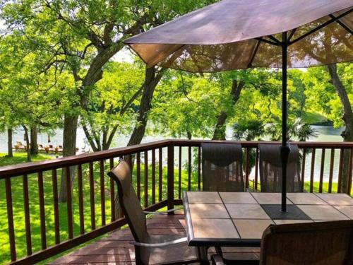 a table and chairs on a deck with an umbrella at The River Haven - Sleeps 32 - on Guadalupe River in Seguin