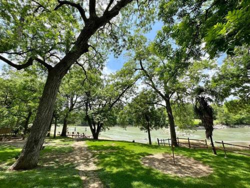 a path through a park with trees and water at The River Haven - Sleeps 32 - on Guadalupe River in Seguin